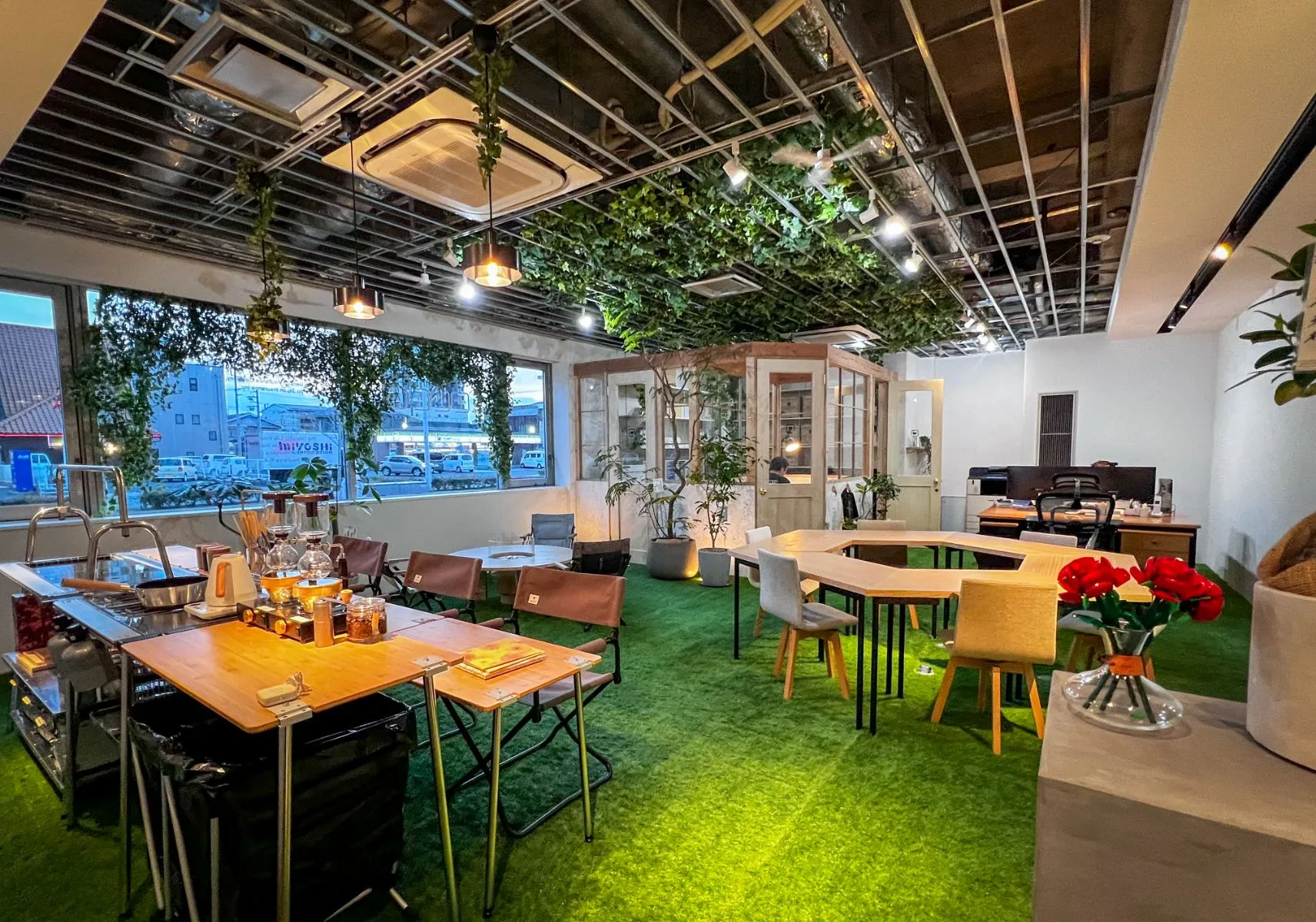 岡崎市、豊橋市の保険代理店、株式会社クワイエットのオフィス。室内には観葉植物が飾られており、緑の床、木のテーブルが置かれています。右の棚には赤い花が飾られています。
